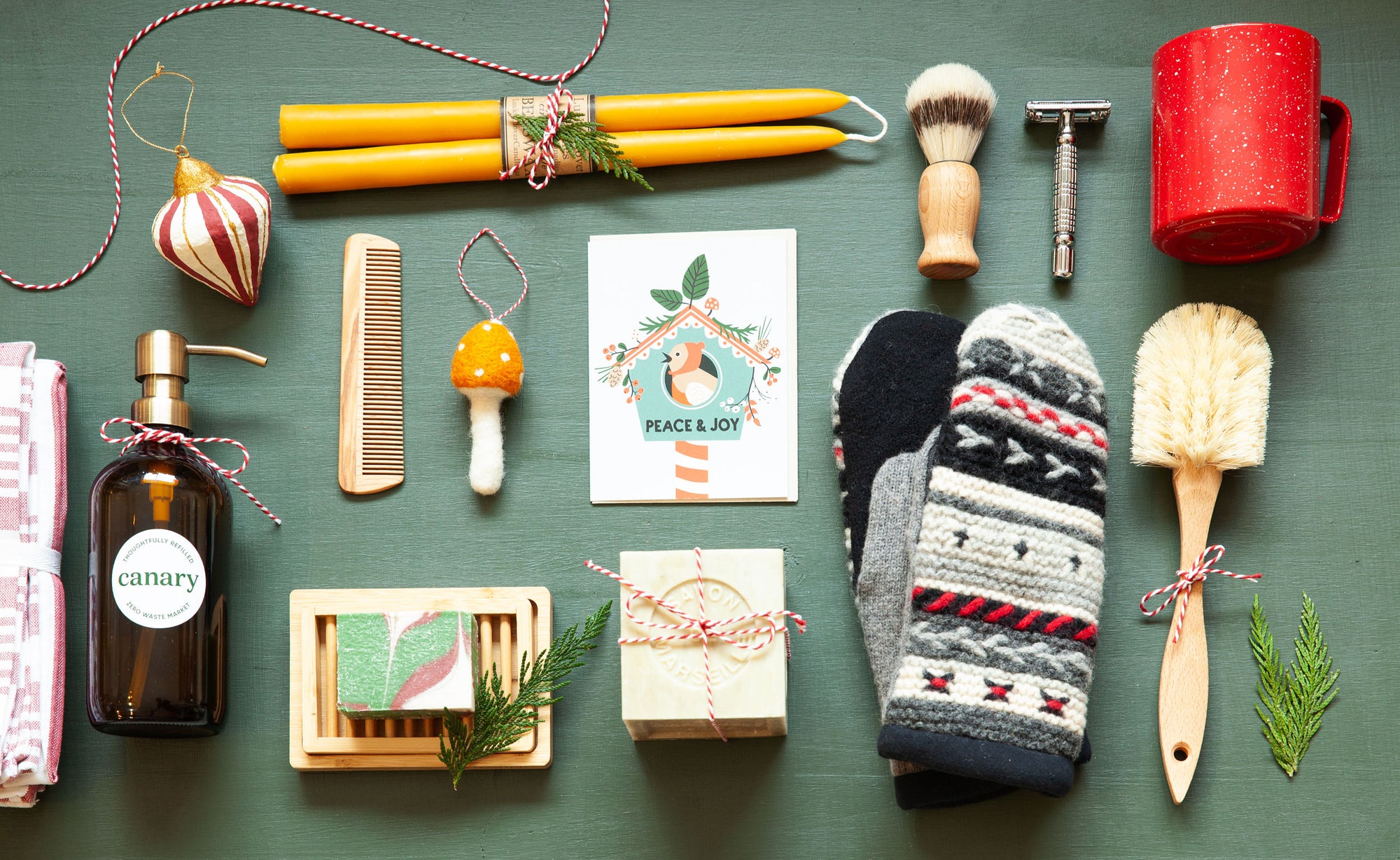 Collection of curated holiday-focused lifestyle items, including a bottle, comb, brush, and socks, on a green surface.