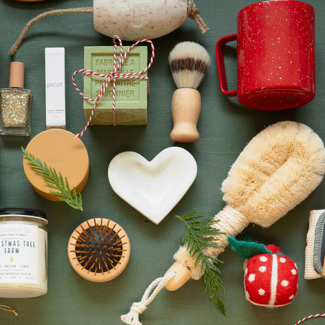 Collection of various items including a red mug, soap, and cleaning tools on a green surface.