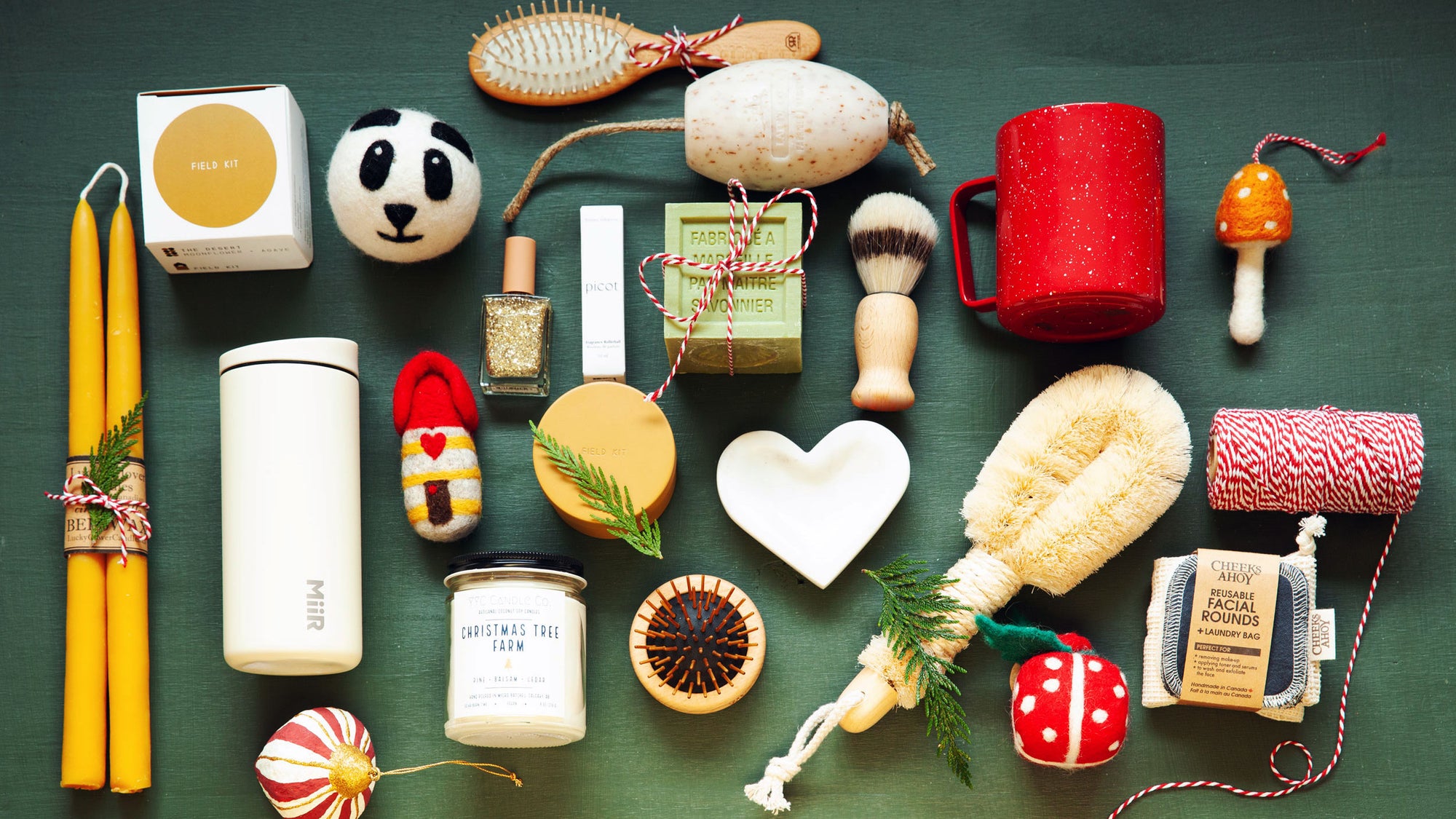 Collection of various items including candles, soaps, and grooming tools on a green background