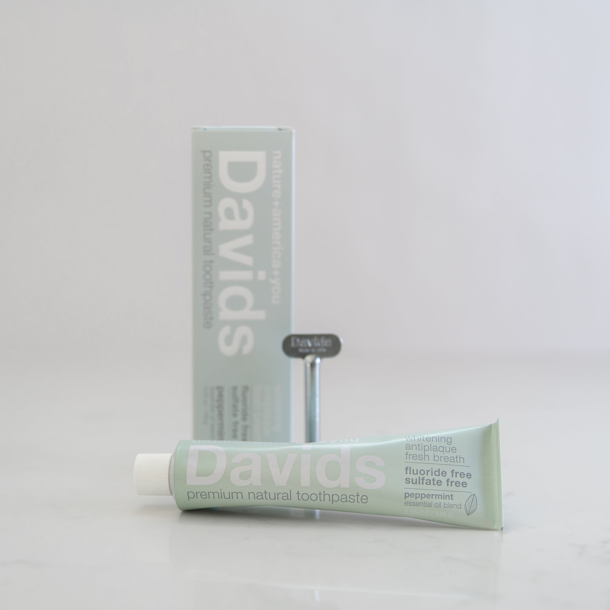 Three tubes of Davids toothpaste stacked vertically, with different flavor labels visible on each tube. The packaging is primarily in shades of blue and white.
