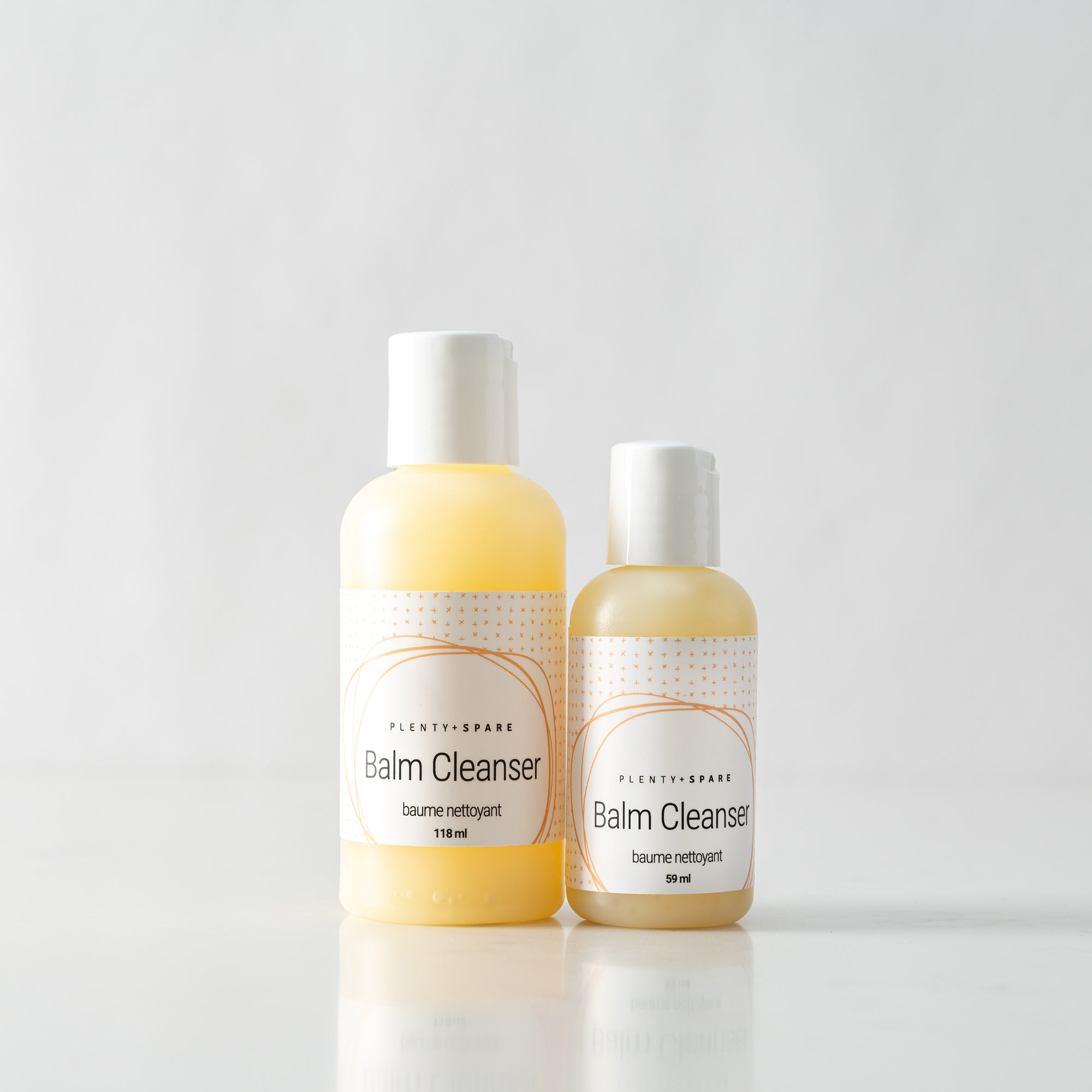 Two bottles of Plenty & Spare Balm Cleanser, one larger and one smaller, against a light background.